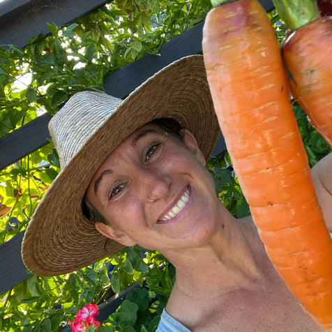 Angie wearing a hat and holding two carrots